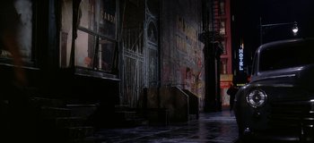 Movie still from “West Side Story” (1961), directed by Jerome Robbins – A dark alley with graffiti on the wall and stairs leading up to it; Extreme Wide shot, High angle