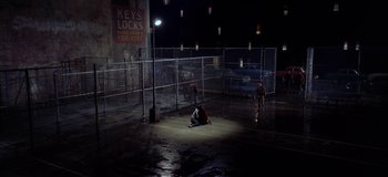 Movie still from “West Side Story” (1961), directed by Jerome Robbins – A group of people sitting in a parking lot at night; Extreme Wide shot, High angle