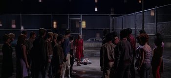 Movie still from “West Side Story” (1961), directed by Jerome Robbins – A group of people standing around a man laying on the ground; Wide shot, High angle