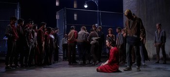 Movie still from “West Side Story” (1961), directed by Jerome Robbins – A group of people gathered around a woman in a red dress; Wide shot, High angle