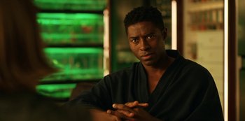 Movie still from “Another Life” (2019), created by Aaron Martin – A man sitting in front of a green background; Close Up shot, Over the shoulder angle