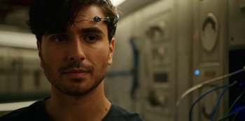 Movie still from “Another Life” (2019), created by Aaron Martin – A person wearing a device on his head; Close Up shot, Over the shoulder angle