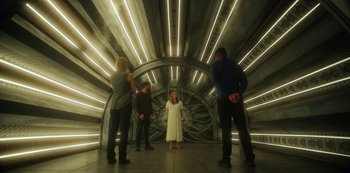 Movie still from “Another Life” (2019), created by Aaron Martin – A group of people standing around a woman in a room; Wide shot, High angle