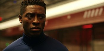 Movie still from “Another Life” (2019), created by Aaron Martin – A person wearing a jacket; Close Up shot, Low angle