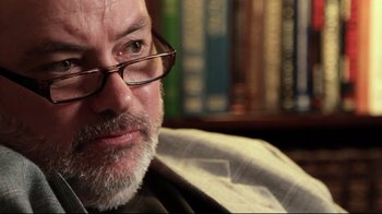 Movie still from “West of Memphis” (2012), directed by Amy Berg – A person wearing glasses and a jacket; Close Up shot, Over the shoulder angle