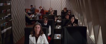 Movie still from “Westworld” (1973), directed by Michael Crichton – A group of people sitting in a row of seats; Wide shot, High angle