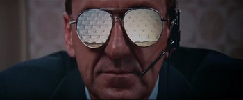 Movie still from “Westworld” (1973), directed by Michael Crichton – A man wearing glasses and a headset with a brick wall reflected in his glasses; Close Up shot, Low angle