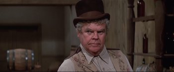Movie still from “Westworld” (1973), directed by Michael Crichton – An older man wearing a top hat and a vest; Close Up shot, Over the shoulder angle