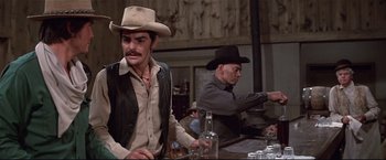 Movie still from “Westworld” (1973), directed by Michael Crichton – Two men in cowboy hats are sitting at a bar; Medium shot, Low angle