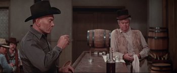 Movie still from “Westworld” (1973), directed by Michael Crichton – Two men sitting at a table in front of a bottle of whiskey; Medium shot, Over the shoulder angle