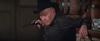 Movie still from “Westworld” (1973), directed by Michael Crichton – A man in a cowboy hat holding a gun; Close Up shot, Low angle