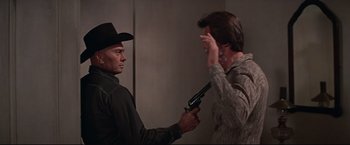 Movie still from “Westworld” (1973), directed by Michael Crichton – Two men in cowboy hats are holding guns; Medium shot, Over the shoulder angle