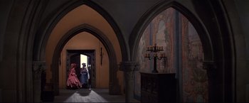 Movie still from “Westworld” (1973), directed by Michael Crichton – Two women in dresses and hats in a room with arches; Extreme Wide shot, High angle
