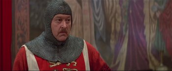 Movie still from “Westworld” (1973), directed by Michael Crichton – A man in a suit of a medieval knight in front of a painting; Close Up shot, High angle