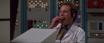 Movie still from “Westworld” (1973), directed by Michael Crichton – A man in a white lab coat eating a donut; Medium shot, Low angle