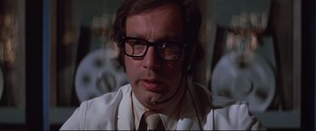 Movie still from “Westworld” (1973), directed by Michael Crichton – A person wearing glasses and a tie; Close Up shot, Low angle