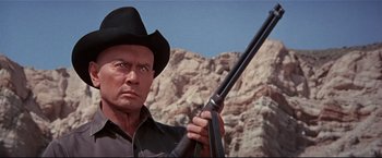 Movie still from “Westworld” (1973), directed by Michael Crichton – A man holding a rifle in front of a mountain; Close Up shot, Low angle