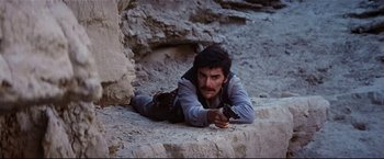 Movie still from “Westworld” (1973), directed by Michael Crichton – A man laying on the ground holding a gun; Medium shot, Low angle