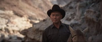 Movie still from “Westworld” (1973), directed by Michael Crichton – A man wearing a cowboy hat standing in front of a rock wall; Medium shot, Low angle