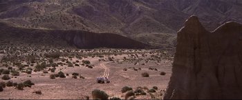 Movie still from “Westworld” (1973), directed by Michael Crichton – A car is driving through the desert near a mountain; Extreme Wide shot, High angle