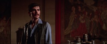 Movie still from “Westworld” (1973), directed by Michael Crichton – A man with a mustache standing next to a painting; Close Up shot, Over the shoulder angle