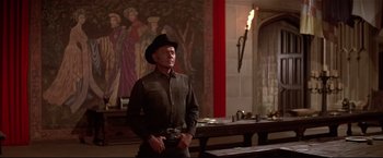 Movie still from “Westworld” (1973), directed by Michael Crichton – A man wearing a cowboy hat standing next to a table; Medium shot, Over the shoulder angle