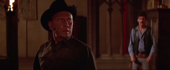 Movie still from “Westworld” (1973), directed by Michael Crichton – A man in a cowboy hat is standing in front of a building; Close Up shot, Over the shoulder angle