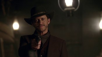 Movie still from “Westworld” (2016), created by Lisa Joy – A man holding a gun while wearing a suit and a hat; Close Up shot, Over the shoulder angle