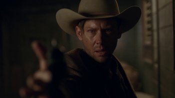 Movie still from “Westworld” (2016), created by Lisa Joy – A man wearing a cowboy hat while holding a gun; Close Up shot, Over the shoulder angle