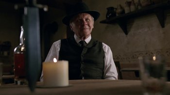 Movie still from “Westworld” (2016), created by Lisa Joy – An old man sitting at a table with a candle in front of him; Medium shot, Over the shoulder angle