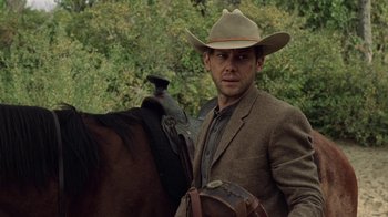 A man wearing a cowboy hat standing next to a horse