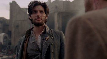 Movie still from “Westworld” (2016), created by Lisa Joy – A man with a long beard standing in front of a stone wall; Close Up shot, Over the shoulder angle