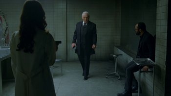 Movie still from “Westworld” (2016), created by Lisa Joy – A man in a suit and tie holding a gun in a room; Wide shot, Over the shoulder angle