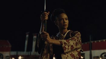 Movie still from “Westworld” (2016), created by Lisa Joy – A woman holding a sword in front of a dark background; Close Up shot, Low angle