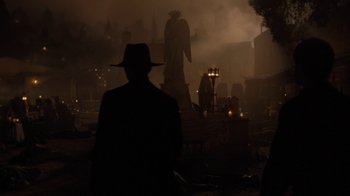 A man wearing a hat standing in front of a statue