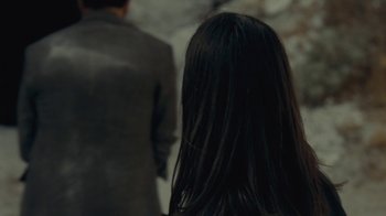 A woman with long black hair standing next to a man
