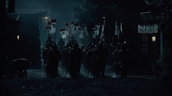 Movie still from “Westworld” (2016), created by Lisa Joy – A group of people are marching in the dark with flags; Extreme Wide shot, High angle