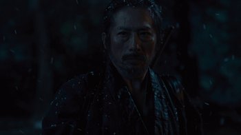 Movie still from “Westworld” (2016), created by Lisa Joy – A man with a long beard and a bow in his hair; Close Up shot, Over the shoulder angle