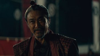 Movie still from “Westworld” (2016), created by Lisa Joy – An older asian man with long black hair; Close Up shot, Over the shoulder angle