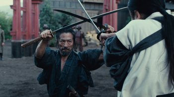 Movie still from “Westworld” (2016), created by Lisa Joy – A man holding a pair of swords up to his face; Medium shot, Over the shoulder angle