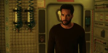 Movie still from “Another Life” (2019), created by Aaron Martin – A man standing in front of a wall; Medium shot, Low angle