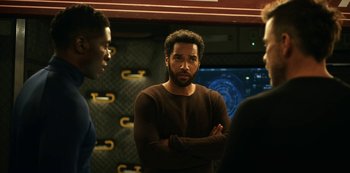 Movie still from “Another Life” (2019), created by Aaron Martin – A man standing next to another man with his arms crossed; Medium shot, Over the shoulder angle