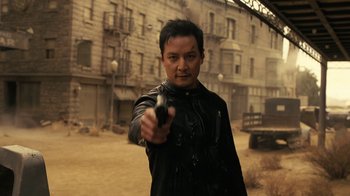 Movie still from “Westworld” (2016), created by Lisa Joy – A man holding a gun while standing on a dirt road; Medium shot, Over the shoulder angle
