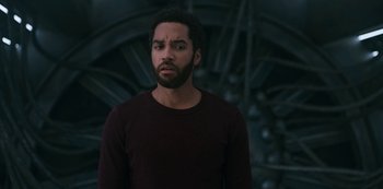 Movie still from “Another Life” (2019), created by Aaron Martin – A man with a beard is standing in front of a building; Close Up shot, Over the shoulder angle