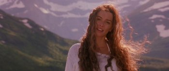 Movie still from “What Dreams May Come” (1998), directed by Vincent Ward – A woman with long red curly hair standing in front of a mountain range; Close Up shot, Low angle