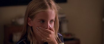 A young girl covers her mouth with her hands