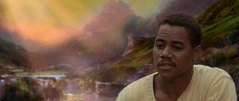 Movie still from “What Dreams May Come” (1998), directed by Vincent Ward – A man standing in front of a painting of mountains; Close Up shot, Low angle