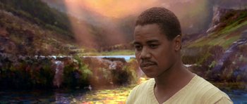 Movie still from “What Dreams May Come” (1998), directed by Vincent Ward – A man in a yellow shirt standing in front of a body of water; Close Up shot, Over the shoulder angle