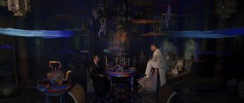 Movie still from “What Dreams May Come” (1998), directed by Vincent Ward – Two men sitting at a table in a room; Wide shot, High angle