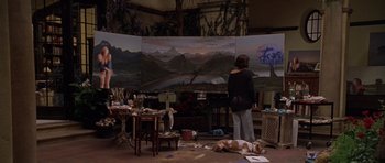 Movie still from “What Dreams May Come” (1998), directed by Vincent Ward – A woman standing in front of a painting in an art studio; Wide shot, Over the shoulder angle